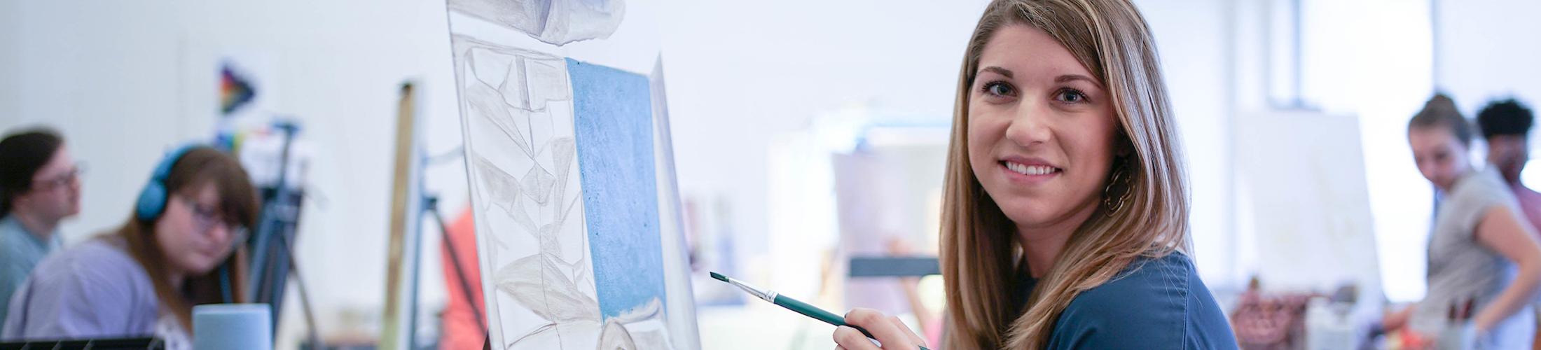 美术课上，学生拿着画笔在她面前画画.
